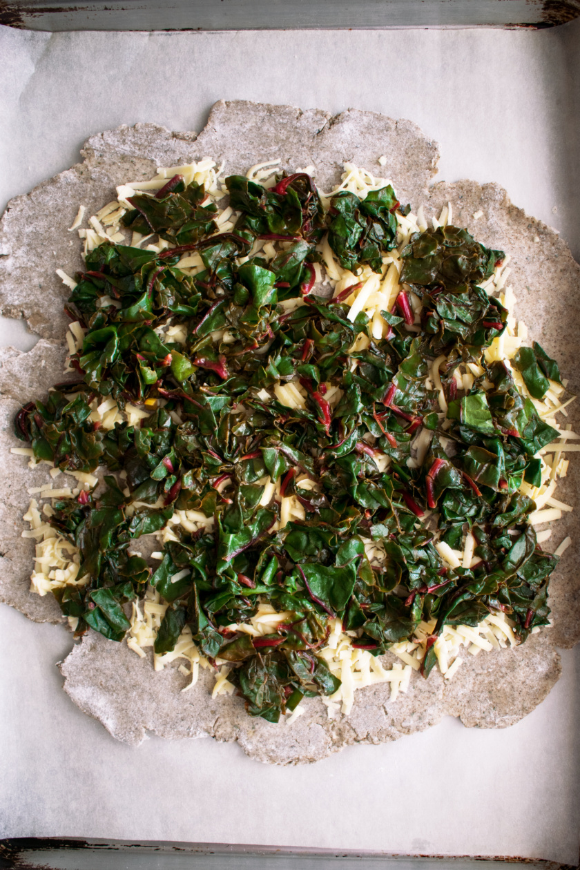 rolled out dough with cheddar cheese and red chard on top